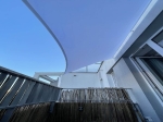 Custom-made waterproof garden sail installed on a terrace above a bamboo fence.