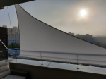 White waterproof custom-made balcony shade sail protects the terrace from the sun against a city skyline.