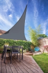 Voile d'ombrage premium grise imperméable en forme de triangle, installée au-dessus d'une terrasse avec mobilier de jardin moderne.