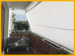 Waterproof custom-made shade sail installed on a balcony as a sunshade over a grey sofa.