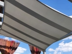 Copertină premium impermeabilă gri deschis, 3x4 m, montată pe o terasă pe fundalul cerului albastru.