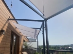 White premium 4x4 waterproof garden sun sail, installed on a terrace above a string of lights.