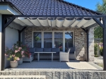 Light grey horizontal premium made-to-measure Roman blind mounted on a graphite terrace structure over garden furniture.