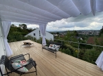 Λευκό οριζόντιο ρωμαϊκό στόρι premium Decor σε βεράντα με θέα στην πόλη, μαύρα έπιπλα και σκύλο στο κρεβάτι του.