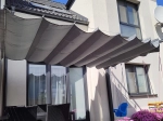Store romand horizontal gris haut de gamme Decor, dimensions 2,5x3 m, installé au-dessus de la terrasse d'une maison moderne.