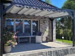 Store romain horizontal gris premium Decor sur une structure de terrasse au-dessus de meubles de jardin et d'une façade en briques claires.
