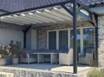 Γκρι οριζόντια ρωμαϊκή κουρτίνα premium Decor 3x4 τοποθετημένη σε γραφίτη πέργκολα πάνω από έπιπλα κήπου στη βεράντα.