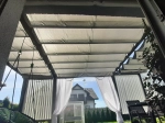 Οριζόντια ρωμαϊκή ρολέτα premium Decor 3x4 m τοποθετημένη πάνω από τη βεράντα, παρέχοντας σκιά μια ηλιόλουστη μέρα.