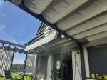 Οριζόντιο premium ρωμαϊκό στόρι Decor 3x4 σε κατασκευή βεράντας δίπλα στο σπίτι με έπιπλα κήπου.