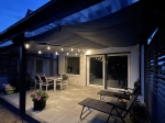 Waterproof premium retractable sail for terrace with lighting, protecting garden furniture after dark.