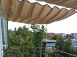 Αδιάβροχο πτυσσόμενο πανί σκίασης 2,5x5 m σε μπεζ χρώμα τοποθετημένο πάνω από βεράντα με θέα στο πανόραμα της πόλης.