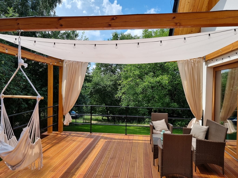 White square sun sail 4.2x4.2m mounted over a wooden terrace with a garden furniture set.