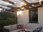 Weißes Sonnensegel-Band 0,75x5 m montiert an einer Holzpergola über der Terrasse mit Gartenmöbeln.