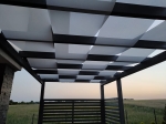 White gazebo sun shade strip 0.75x5 m interwoven through the beams of a modern garden pergola.