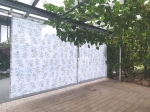 Tenda velata su misura con motivo a foglie, appesa a una moderna pergola da terrazza con viti.