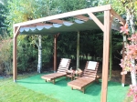 Store romain horizontal en PVC imperméable sur mesure, installé sur une pergola en bois dans un jardin.