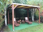 Houten terrasoverkapping voor het hele jaar met beige PVC-doek, waaronder ligstoelen op kunstgras staan.