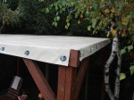 PVC terrasoverkapping op maat voor het hele jaar, gemonteerd op een houten constructie met metalen ringen.