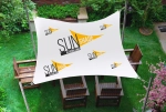 Vela pubblicitaria impermeabile personalizzata con grafica SUNSHADE sopra mobili da giardino in legno sul prato.