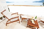 Brise-vue de balcon blanc monté sur une rambarde de terrasse avec vue sur la mer et mobilier de jardin.