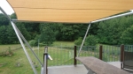 Sand-coloured HDPE sun sail made to measure, installed on the terrace over a garden table.