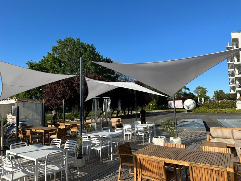 Voiles d'ombrage triangulaires imperméables premium, ombrageant une terrasse moderne avec mobilier de jardin.