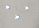 Primer plano de los ojales metálicos incrustados en el material beige de la vela de sombra impermeable a medida.
