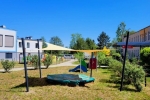 Custom-made shade sails over a sandbox at a colourful playground near kindergarten buildings.