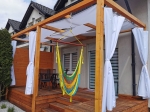 Modern bir terasta hamaklı ahşap pergola üzerine monte edilmiş özel yapım beyaz su geçirmez perde.