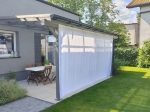 Tenda impermeabile bianca su misura installata su una terrazza moderna con pergola e mobili da giardino.