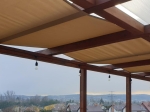 Aydınlatmalı ahşap pergola üzerine monte edilmiş, terası yağmurdan koruyan özel yapım su geçirmez çardak bandı.