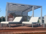 Terasta şezlongların bulunduğu modern bir pergola üzerine monte edilmiş özel yapım su geçirmez çardak bandı.