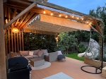 Οριζόντια premium ρωμαϊκή κουρτίνα Decor 2,5x3 τοποθετημένη κάτω από ξύλινη πέργκολα σε βεράντα με έπιπλα κήπου.