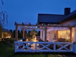 Λευκό οριζόντιο ρωμαϊκό στόρι Premium Decor σε βεράντα με πέργκολα, ηλιακή προστασία στον κήπο μετά το σούρουπο.