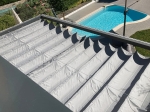 Γκρι οριζόντια premium ρωμαϊκή κουρτίνα Decor πάνω από τη βεράντα, με πισίνα κήπου στο βάθος.
