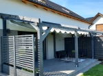 Ανοιχτό γκρι οριζόντιο ρωμαϊκό στόρι Premium Decor διαστάσεων 2,5x3 m τοποθετημένο σε μοντέρνα ξύλινη πέργκολα.