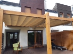 Μπεζ οριζόντια ρωμαϊκή κουρτίνα Premium Decor 3x4 τοποθετημένη σε ξύλινη πέργκολα πάνω από τη βεράντα με έπιπλα κήπου.