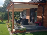Horizontal premium Decor 4x4 Roman blind mounted on a wooden pergola over a terrace with garden furniture.