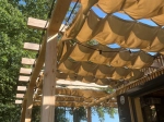 Vela de jardim impermeável retrátil 1,5x5 m montada numa pérgola de madeira com iluminação de grinalda.