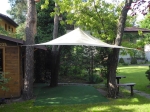 Voile d'ombrage triangulaire premium imperméable sur mesure, installée au-dessus d'un coin détente dans le jardin.