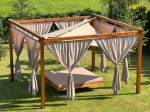 Vela ombreggiante triangolare beige 5,2x5,2x5,2m montata sopra un gazebo in legno con letto sospeso in giardino.