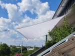 White premium waterproof shade sail 3x4 m installed on a terrace, providing sun protection against the sky and rooftops.