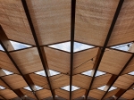 Brown HDPE sunshade sail on a wooden terrace roof with atmospheric garden lights.