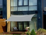 Vela ombreggiante grigio-verde HDPE 3x3 sulla terrazza di una casa moderna con due poltrone sullo sfondo.