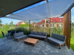 Kaasaegne kaubaalustest mööbliga terrass, varjatud valge säästliku eritellimusel päikesepurjega.