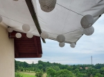 Wit, voordelig schaduwdoek op maat, opgehangen boven een terras met decoratieve lampionnen.