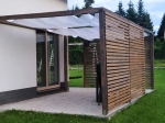 Voile d'ombrage blanche rétractable sur mesure montée sur une pergola de terrasse en bois près d'une maison moderne.