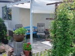Baltas ištraukiamas burinis tentas nuo saulės 1,5x5 m, sumontuotas terasoje virš poilsio zonos su baldais.