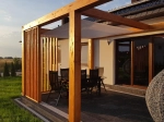 Velă de umbrice albă 3,2x4,2 m montată pe o pergolă de lemn deasupra unei terase cu set de mobilier de grădină.