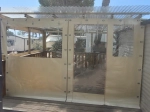 Custom-made transparent terrace cover with beige trim and PVC windows mounted on a wooden terrace.